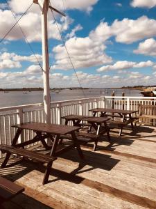 克劳奇河畔伯纳姆Ye Olde White Harte Hotel的三个野餐桌坐在靠近水面的码头上