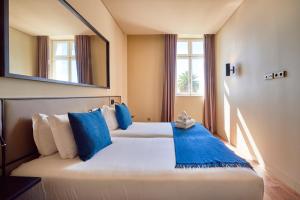 里斯本里斯本五星公寓 - 8号楼的一间卧室配有两张带蓝色枕头和镜子的床