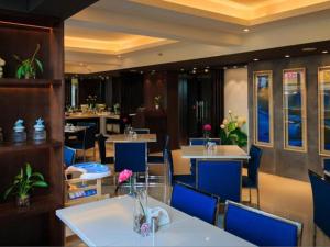 杭州JinJiang Inn Hangzhou Road subway station Xiasha High Fashion Hotel的一间带桌子和蓝色椅子的用餐室以及一间餐厅