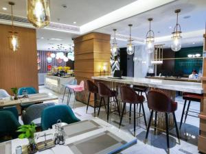 贵阳Magnotel guiyang fountain commercial center subway station hotel的餐厅设有酒吧,配有一些桌椅