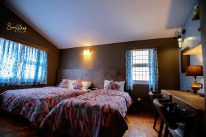 科代卡纳尔snow drop villa的一间卧室配有两张床、一张桌子和两个窗户。