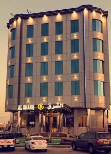 哈费尔巴廷Al Sharq Hotel的前面有汽车停放的建筑