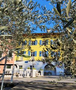 布鲁西诺亚希吉欧Dolceresio Lugano Lake B&B的一座黄色和白色的建筑,前面有一棵树