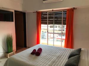 莫龙Cares Apartament, Morón, Buenos Aires的一间卧室配有一张带红色拖鞋的床