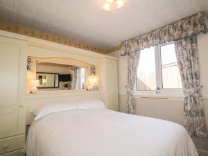 InverBraemar Cottage的卧室配有白色的床和窗户。