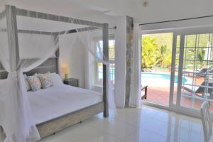 马里戈特湾马里戈棕榈加勒比海豪华公寓套房酒店的一间卧室设有天蓬床和一个游泳池