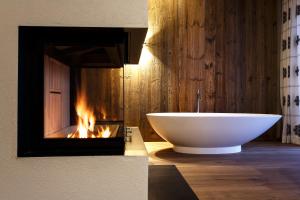 埃尔毛伊尔玛因提洛尔运动酒店的带浴缸的浴室和壁炉。