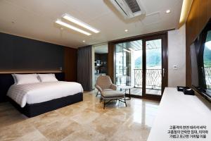 旌善Pine Forest Jeongseon Alpine Resort的一间带一张床和一把椅子的卧室以及一个阳台