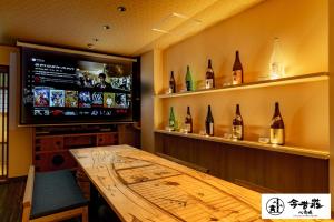 大阪Konjaku-So Shinsaibashi Rooftop SPA的一间带木桌和电视的用餐室