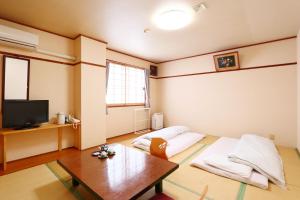 熊野市见晴亭商务酒店的客厅配有2个枕头和桌子