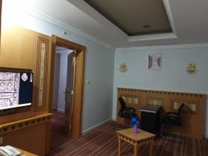 麦加EWG Rahaf Al Mashaer Hotel的配有电视和桌椅的房间