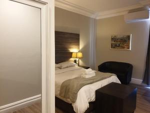 德班Andaluz Boutique Hotel的一间卧室配有一张床、一把椅子和镜子