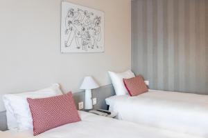 阿尔法法尔宜必思瓦伦西亚阿法法酒店的两张位于酒店客房的床,配有红色和白色枕头