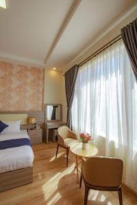大叻Khanh Uyen 1 Hotel的一间卧室配有一张床、一张桌子和一个窗户。