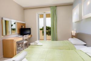 卡尔扎迈纳君主海滩酒店的一间卧室配有两张床、一张桌子和一台电视。