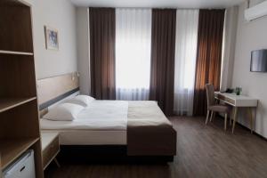 库尔斯克Отель "Даймонд Луговая"的配有一张床、一张书桌和一扇窗户的酒店客房