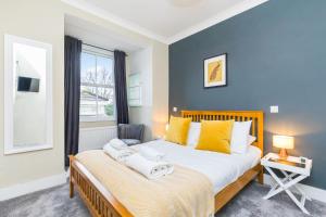 HurstpierpointMorleys Rooms - Located in the heart of Hurstpierpoint by Huluki Sussex Stays的一间卧室配有一张带黄色枕头的大床和窗户。