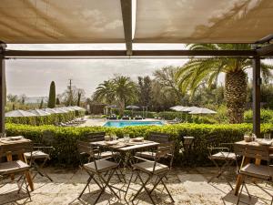 托伦特Mas de Torrent Hotel & Spa, Relais & Châteaux的一个带桌椅的庭院和一个游泳池