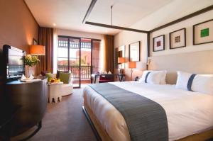 马拉喀什Hôtel Du Golf Rotana Palmeraie的酒店客房设有一张大床和一台电视。