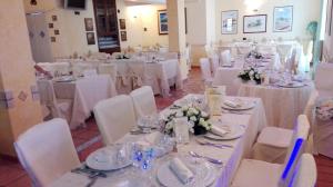 佩塔恰托Hotel Di Nardo的一间设有桌椅和白色床单的房间