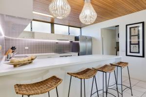 科夫斯港鹦鹉螺海滨Spa公寓的厨房配有白色的柜台和凳子