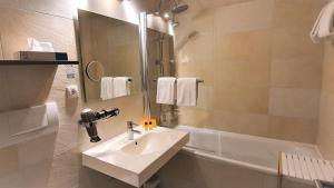 林道迈克斯酒店的浴室配有水槽、淋浴和浴缸。