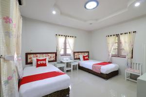 南奔OYO 553 Kongsup Resort的一间卧室配有两张带红白色枕头的床