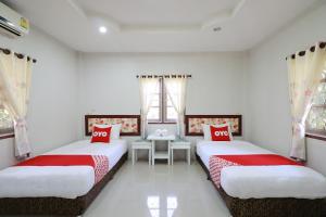 南奔OYO 553 Kongsup Resort的配有2张床的白色墙壁和窗户客房