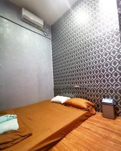 芝拉扎Cilacap Guest House的小房间设有一张带墙壁的床