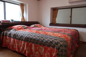萩市萩ゲストハウスラビット的一间卧室配有一张带红色毯子的床和两个窗户。