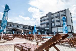 蒂米什瓦拉冰雪SPA度假酒店的大楼前的游泳池,配有椅子和蓝色遮阳伞