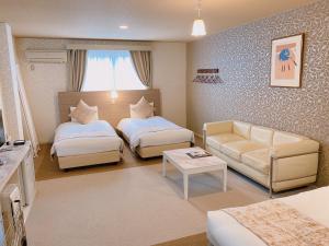 轻井泽Sora Hotel Karuizawa Outlet的一间带两张床和一张沙发的客厅