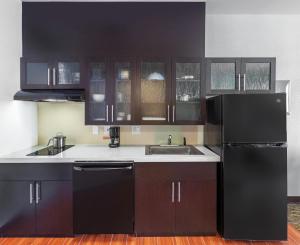 休斯顿Candlewood Suites Houston - Spring, an IHG Hotel的厨房配有黑色橱柜和水槽