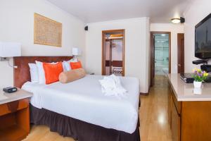 波哥大兰开斯特宫酒店的卧室配有一张白色大床和电视。