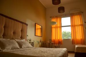 瓜亚基尔曼索精品宾馆的一间卧室配有床和橙色窗帘的窗户