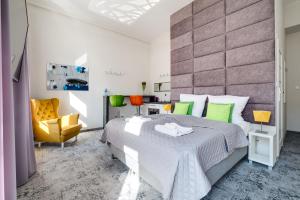 卡托维兹SAVOY Mariacka Apartments的一间卧室配有一张大床和一张黄色椅子