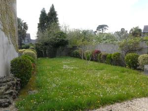 贝诺代Ker Corentine, maison de charme à Benodet, jardin的草地和鲜花的院子和栅栏