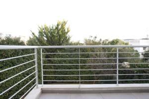 雅典Voula, A modern, minimal and stylish, apartment的树后阳台的围栏