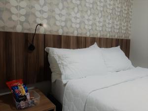 龙多诺波利斯Hotel Horto的一张带白色床单的床和一张桌子上的台灯