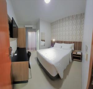 龙多诺波利斯Hotel Horto的卧室配有一张白色大床和电视。