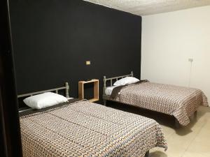 贾拉普Posada Loreto Xalapa的一间卧室设有两张床和黑色的墙壁