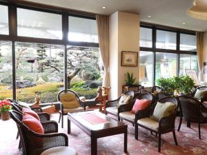 千曲市上山田酒店的客厅配有家具和大窗户。