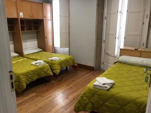 圣地亚哥－德孔波斯特拉PR Paz de Agra的客房 - 带两张带绿毯的床和木地板