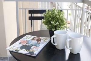 雅典Zan Moreas, A simple & minimal apartment的一张桌子,上面有杂志和两个杯子