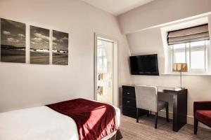 埃克塞特埃克塞特鲁日蒙美居酒店的酒店客房配有一张床、一张书桌和一台电视。