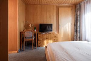 采尔马特欧陆酒店的一间卧室配有一张床和一张书桌及电视