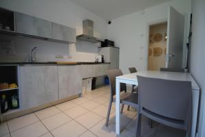 特伦托Komodo short stay apartments的厨房配有白色的桌子和一些椅子
