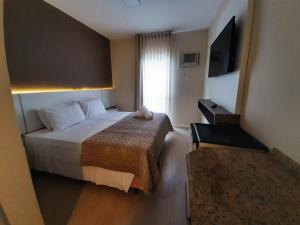 弗洛里亚诺波利斯Caravaggio Praia Hotel的酒店客房,配有床和电视