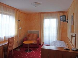 瓦勒湖畔诺伊马克特荷索度假酒店的酒店客房配有一张床、一把椅子和一张书桌