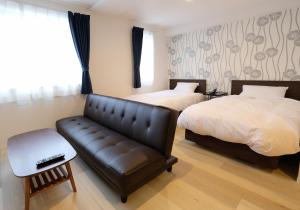 小樽Cozy Inn OTARU的酒店客房带两张床和真皮沙发